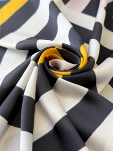 Macro shot of striped silk scarf with black white and yellow geometric patterns