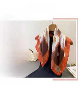 Detail view of checkerboard silk scarf with luxury chain and lion emblem patterns