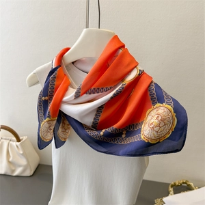 Detail of silk satin scarf with orange and blue checkerboard print and golden lion head pattern