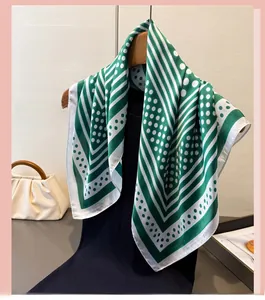 Detail of green and white polka dot silk scarf draped on a wooden hanger with accessories