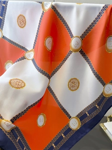 Detailed view of checkered silk scarf with lion head crest and chain pattern design