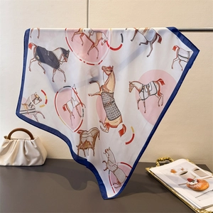 Detailed view of elegant horse print silk scarf draped over a gold decorative tray