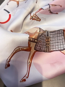 Close-up of silk scarf with orange horse equestrian print and smooth fabric texture