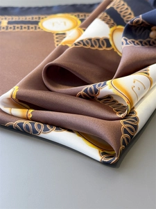 Macro shot of silk scarf detailing luxury chain patterns and gold emblem prints