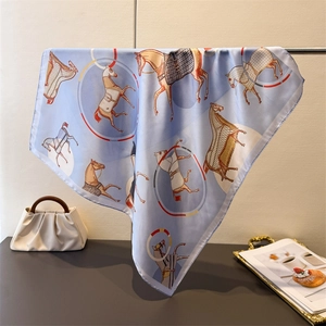 Detail of light blue silk-like scarf with equestrian horse prints and horse gear patterns