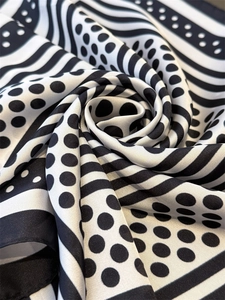 Macro detail of silk-like square scarf featuring elegant polka dots and wave patterns