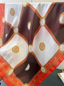 Detail of silk scarf showing gold chain patterns and lion head motifs with soft satin sheen