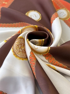 Macro detail of silk scarf showing golden lion head motifs and chain print textures