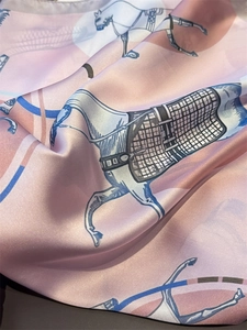Detail of pink silk scarf showing elegant equestrian horse and bridle patterns