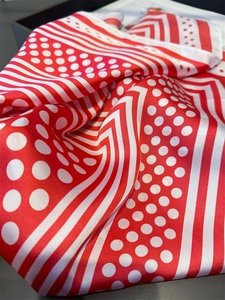 Detailed view of red and white polka dot silk scarf with elegant geometric stripes