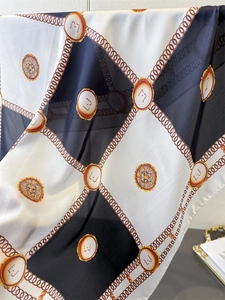 Close-up of checkers pattern silk scarf with golden chain and lion head emblem details