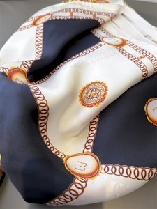 Detail of silk-feel scarf featuring golden chains, lion emblems and black-white patterns