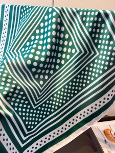 Close-up of green and white polka dot silk scarf with elegant satin finish and fine texture