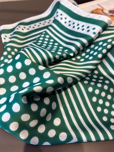 Detail of green and white polka dot silk scarf with elegant striped pattern texture