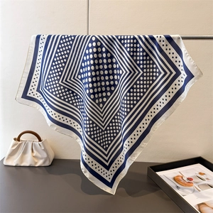 Detailed view of navy blue polka dot silk scarf draped over a metal rod for luxury look