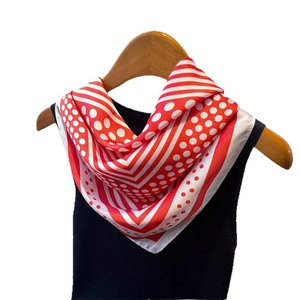 Red and white polka dot faux silk neck scarf displayed on a wooden hanger with model