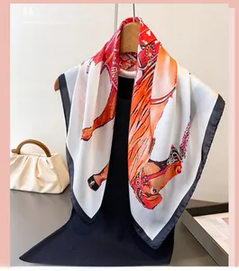 Close-up of silk-like square scarf featuring equestrian horse prints and vibrant orange borders