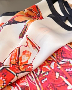 Detailed close-up of equestrian silk square scarf with artistic print and black hem