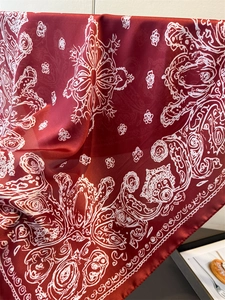 Detailed macro view of the silky burgundy scarf with white paisley mandala patterns