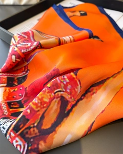 Detail of elegant equestrian print silk scarf with vibrant orange satin and navy edge