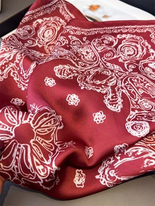 Close-up of red paisley silk scarf showing elegant satin texture and intricate patterns
