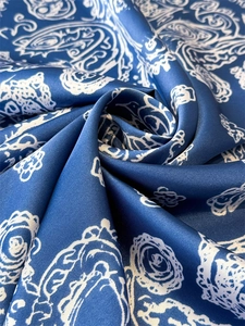 Detailed close-up of dark blue silk scarf featuring white paisley patterns and satin texture