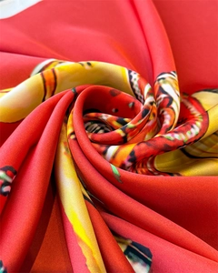 Macro shot of silk scarf fabric showing luxurious red swirls and equestrian print detail