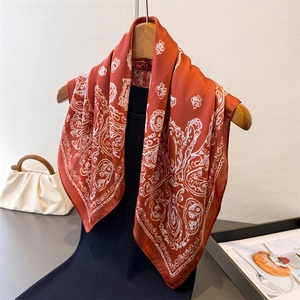 Luxurious red silk scarf with white bohemian print hanging on a wooden hanger