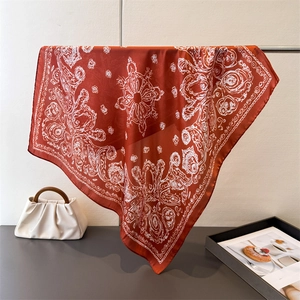 Detail of red paisley silk scarf with white floral patterns draped on a metal stand