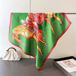 Detail view of a luxury silk-like scarf with equestrian horse print and green silk texture