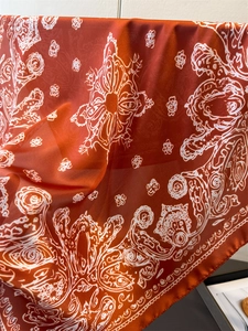 Detail of orange satin scarf showing elegant paisley patterns and silky texture draping