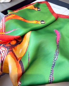 Close-up of silk scarf with equestrian prints, green satin texture and red borders