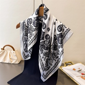 Elegant white silk square scarf with black cashew paisley floral print on wooden hanger