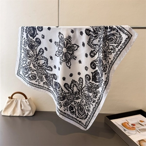 Detail of vintage paisley silk-like square scarf featuring black patterns on white fabric