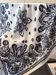 Detail of paisley print silk scarf showing smooth satin texture and rolled hem edges