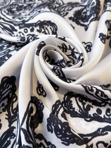 Close-up of elegant black and white baroque print faux silk scarf with glossy texture