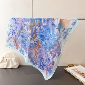 Detailed view of elegant blue and purple floral silk scarf hanging on a metal rack