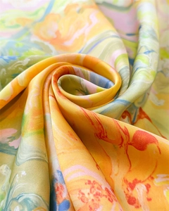 Detail shot of swirling faux silk fabric with vibrant orange and yellow marble print texture