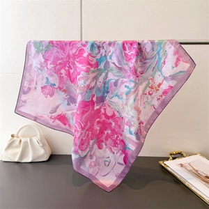 Detail of silk-like square scarf with abstract pink and blue floral print draped on rack