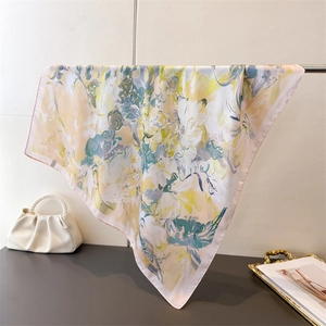 Detail of silk-like square scarf with floral print draped beside a pearl handle bag