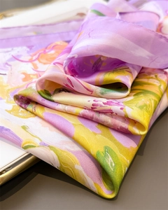 Detail of silk-like scarf with violet floral print showing soft texture and smooth drape