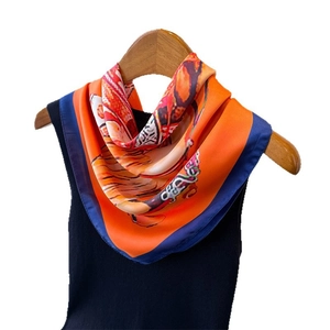 Silk scarf with equestrian print on wooden hanger with blue knit shirt backdrop