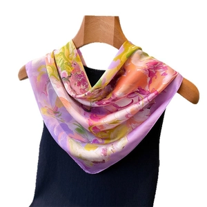 Abstract floral silk square scarf with vibrant purple and orange patterns on wood hanger