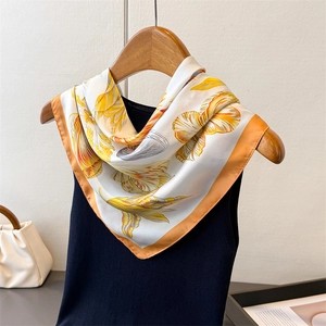 Elegant lily floral print silk scarf in yellow and orange tied on a black top