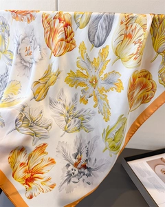 Close-up of silk scarf with yellow tulips print and premium orange rolled edges