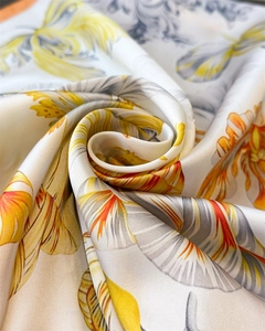 Macro detail of luxury satin scarf featuring abstract yellow and orange feather floral print