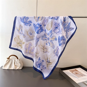 Detail of silk-like scarf featuring blue tulip patterns and deep blue borders hanging