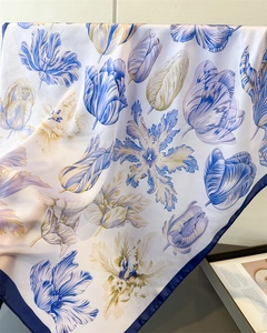 Detail of silk-like satin scarf featuring blue and yellow tulip prints and navy borders
