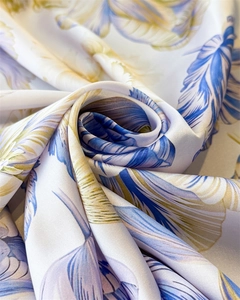 Macro detail of elegant silk scarf showing feather print on high-gloss textile surface