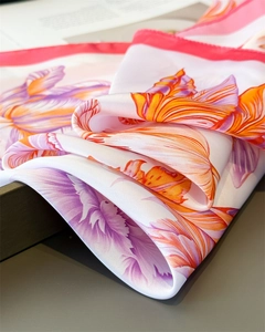 Detailed view of white silk scarf with vibrant tulip prints and refined pink edge stitching